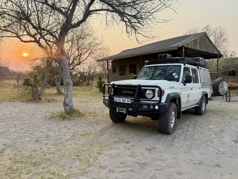 Geländewagen mit Dachzelt bei Sonnenuntergang im Camp
