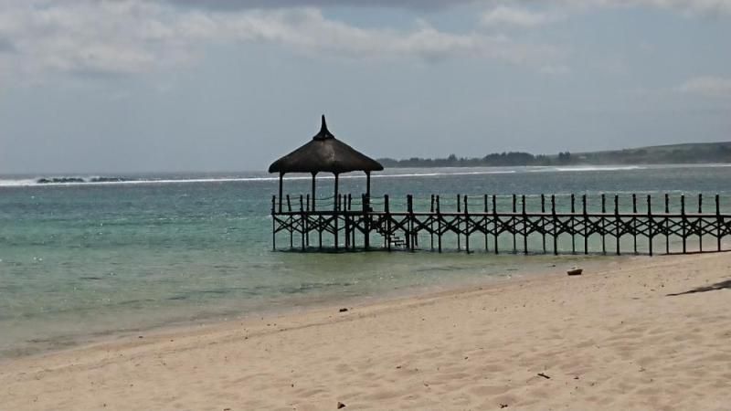 Strohgedeckter Pavillon am Steg über dem türkisen Meer