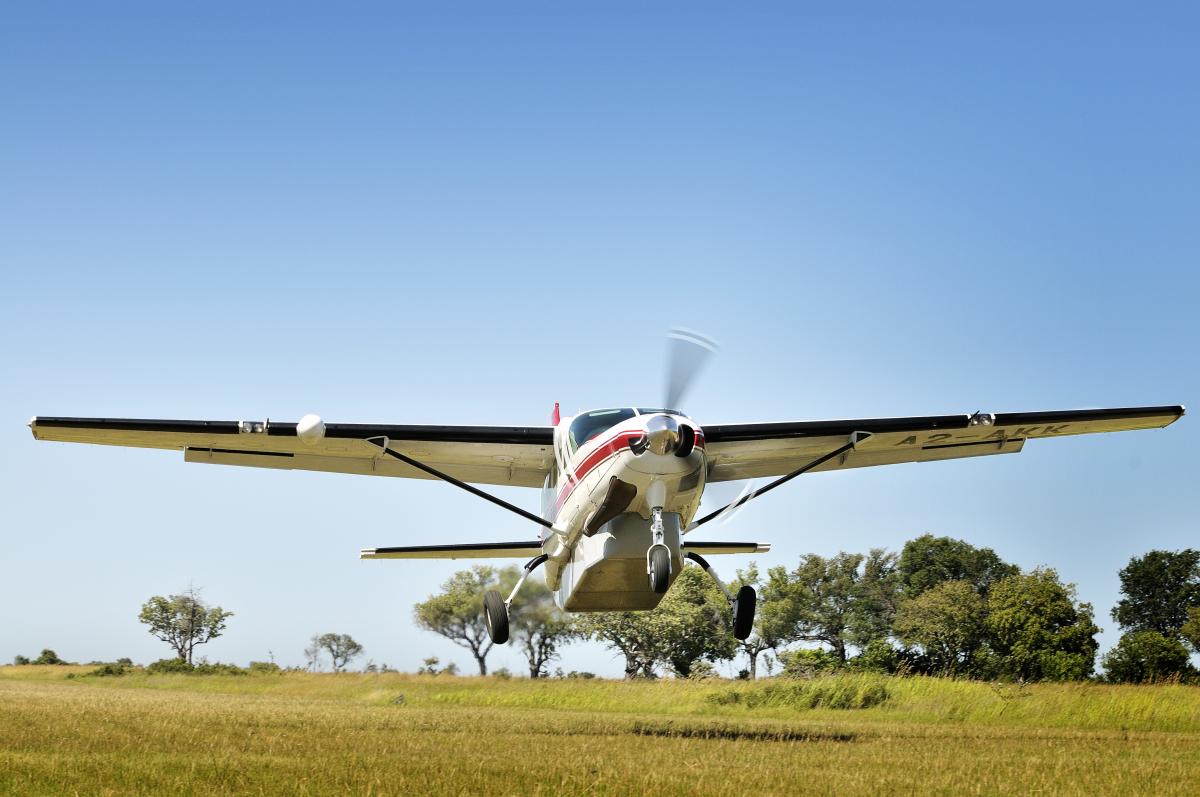 Flugzeug des Typs Propelormaschine hebt ab in die Flitterwochen vom Rollfeld in Afrika in der Savanne