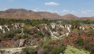 Die Ausläufe der Epupa Fälle in Namibia ziehen sich wie grüne Bänder durch die aride Landschaft des Kaokoveldes